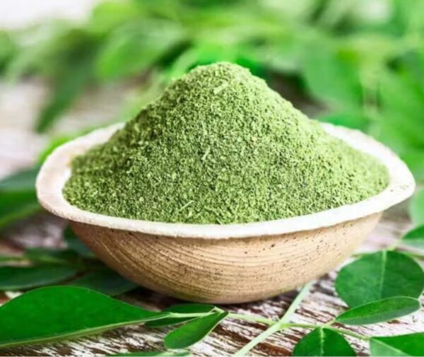 Bowl of vibrant green moringa powder with a teaspoon
