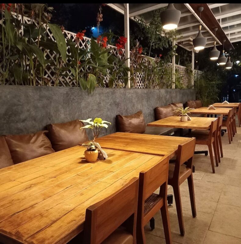 The glasshouse interior and lush greenery inside Green Theory Cafe Bangalore.